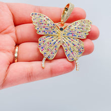 Load image into Gallery viewer, May include: Multicolored butterfly pendant.  The pendant is gold-toned with a detailed butterfly design.  The butterfly's wings are encrusted with small, sparkling stones in shades of pink, blue, yellow, and clear. The pendant features a detailed body and antennae.  The pendant is a statement piece of jewelry.
